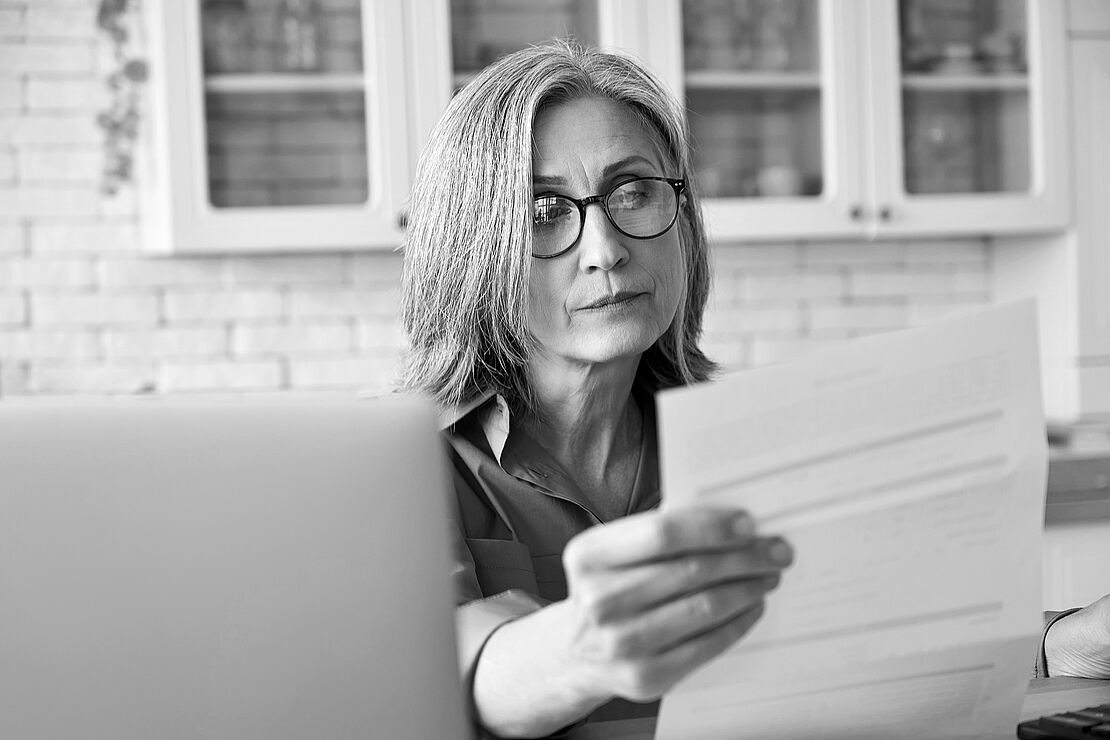 Frau vor PC mit Dokument in der Hand